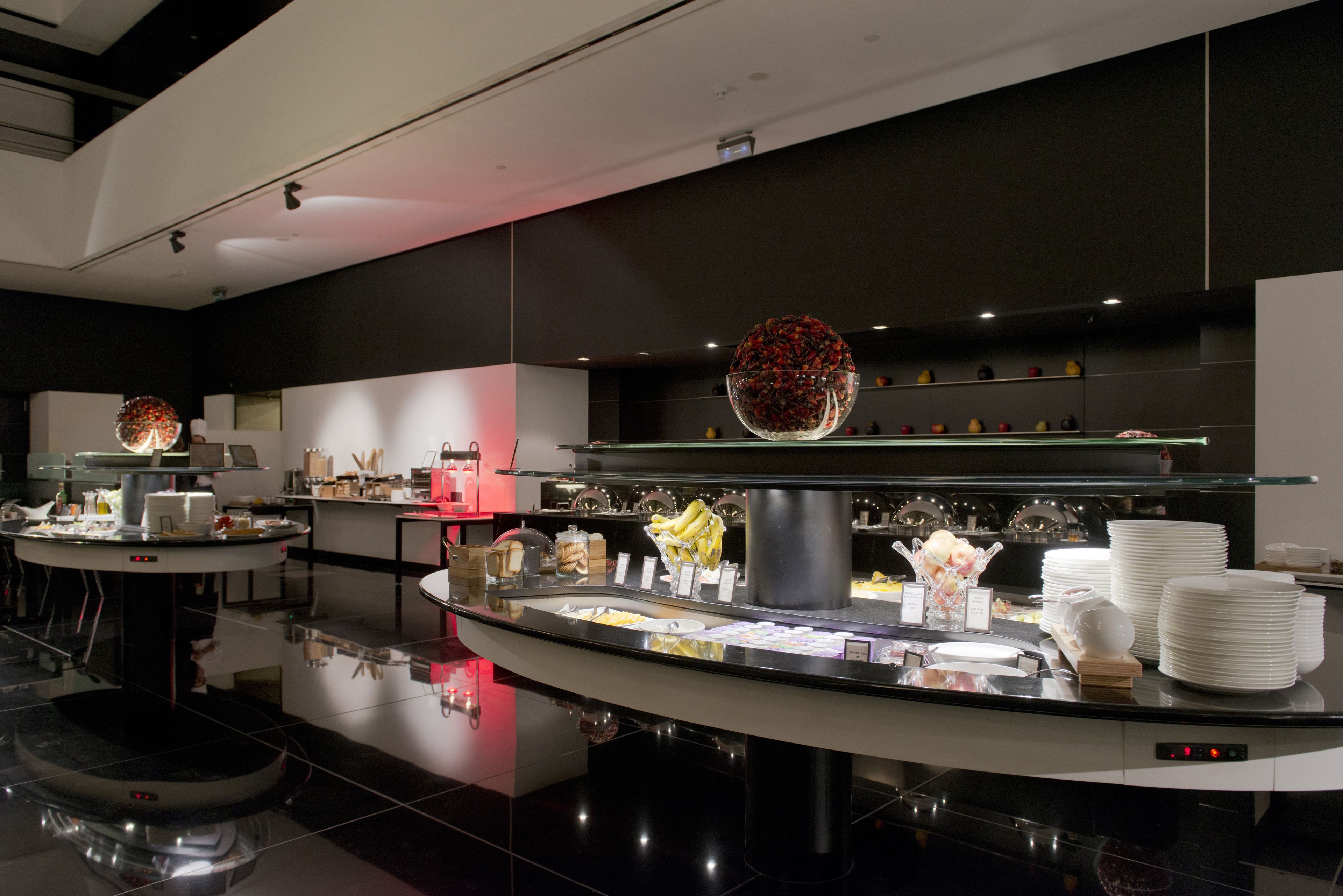 Un espace buffet moderne et bien éclairé, proposant une variété de plats et agrémenté d’un grand vase décoratif placé au centre.