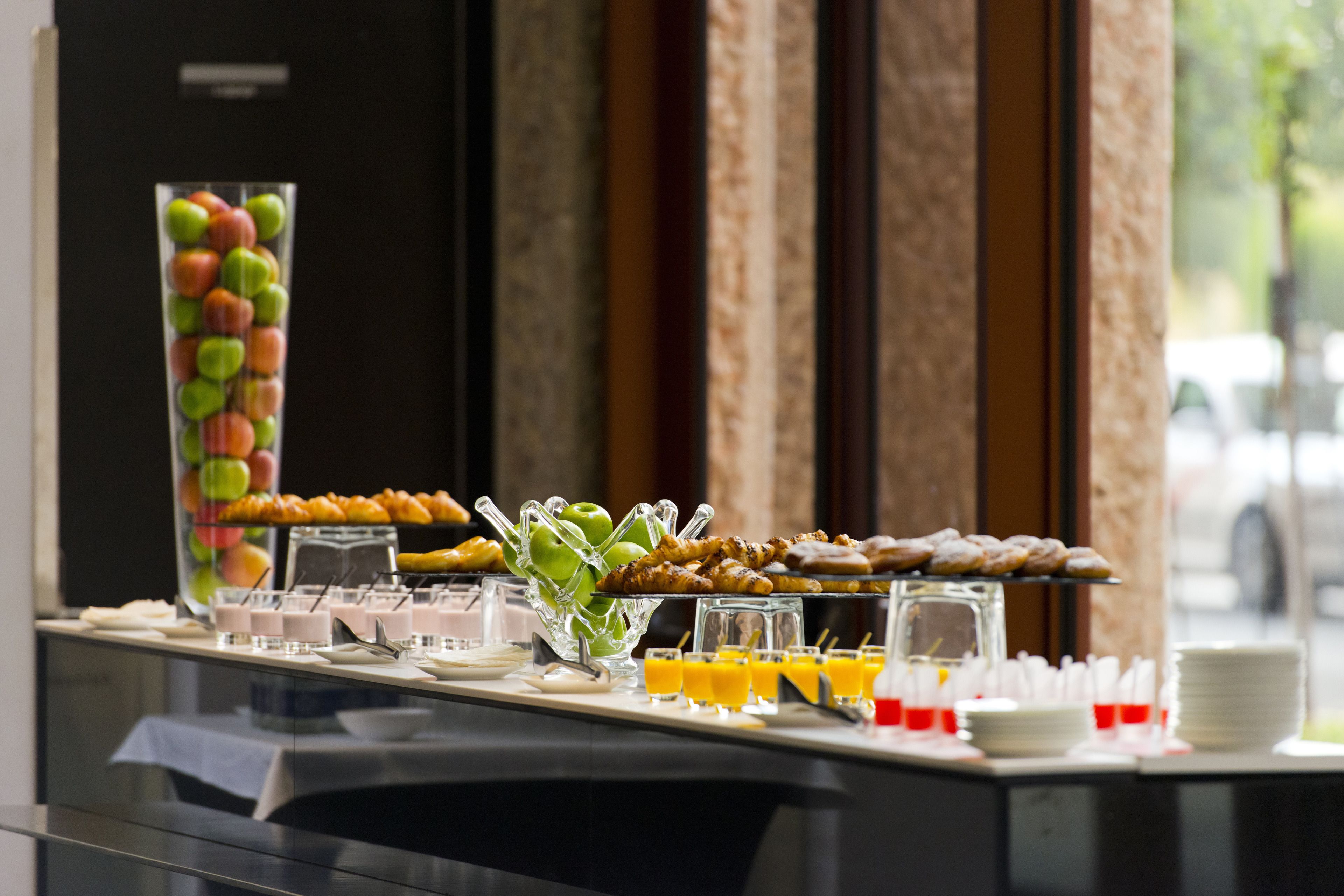 A buffet with various food items and beverages, including fruits, pastries, and juices.