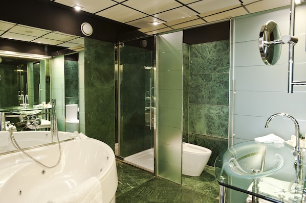 A modern bathroom with a glass-enclosed shower, a freestanding bathtub, and a glass sink. - Hilton Madrid Airport (Madrid)