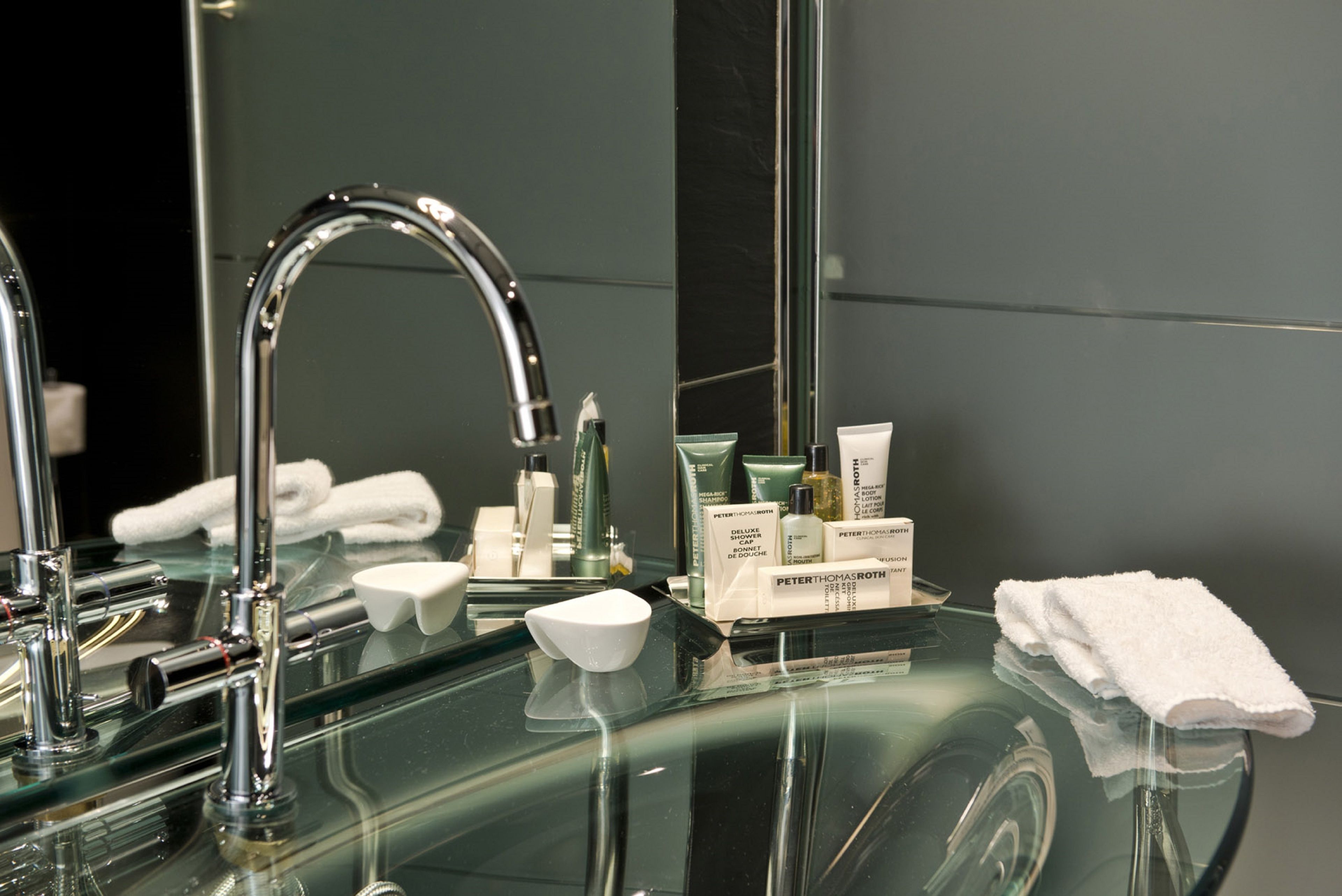 A modern bathroom with a glass sink, a chrome faucet, and neatly arranged toiletries.