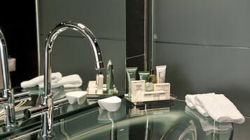 A modern bathroom with a glass sink, a chrome faucet, and neatly arranged toiletries.