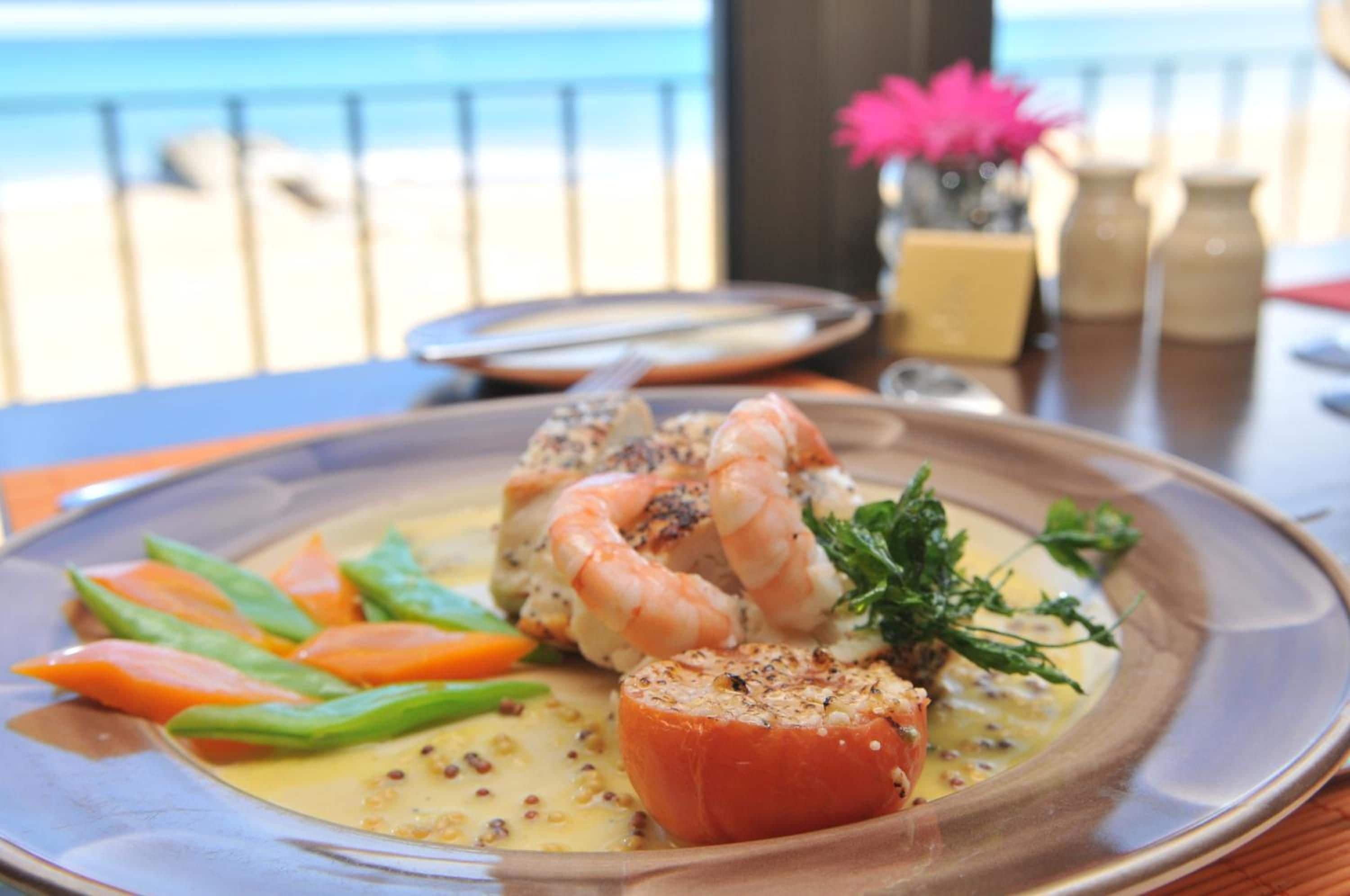 Un plato de mariscos con camarones, verduras y tomate.