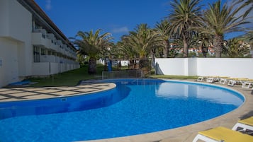 Una piscina al aire libre, sillones reclinables de piscina