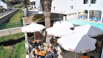 Un espacio al aire libre con sombrillas, una piscina y vistas a una calle residencial.