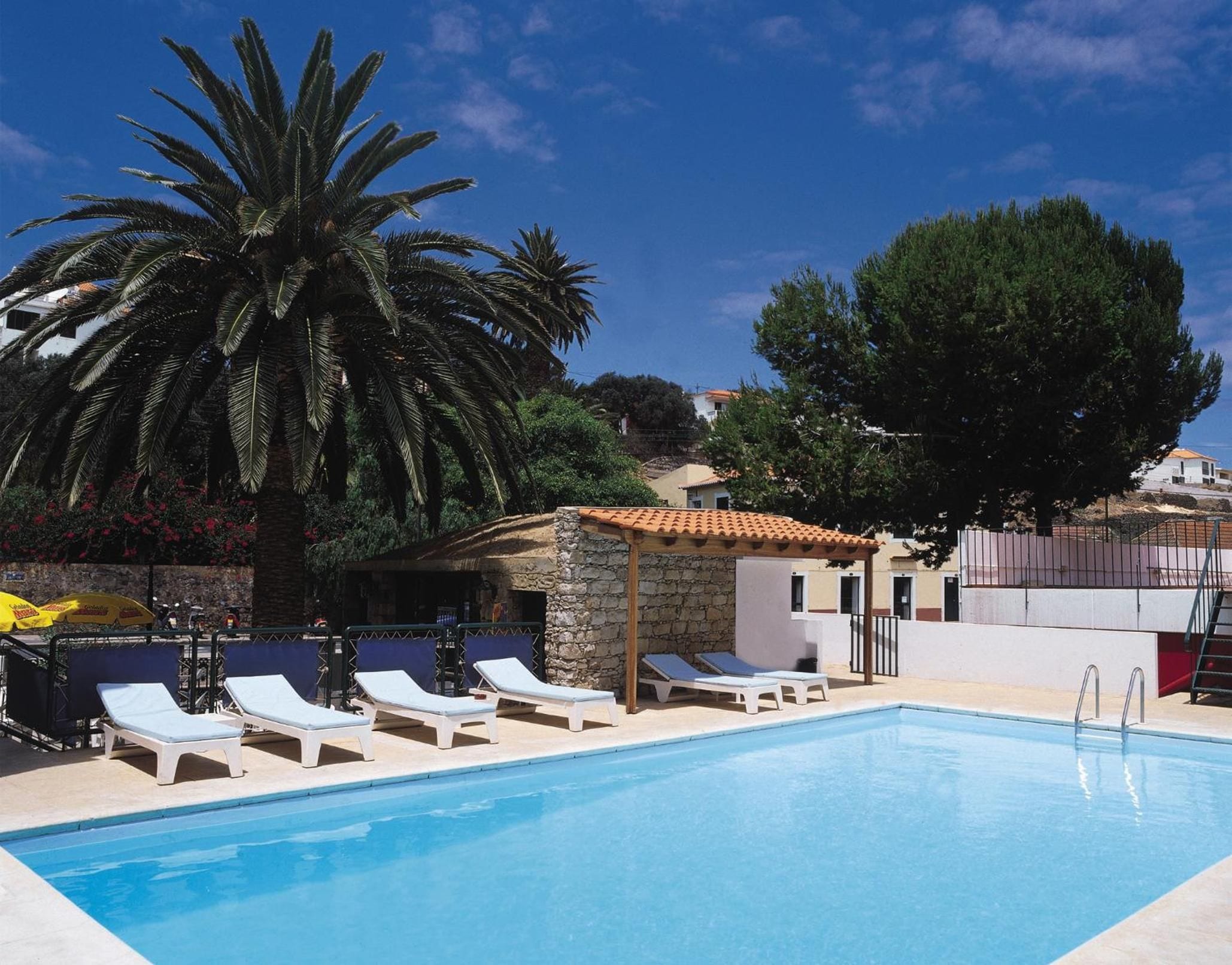 A swimming pool with lounge chairs and a stone structure.