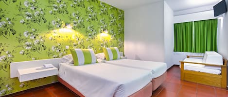 Una habitación de hotel con dos camas, una mesita de noche pequeña, una silla, un televisor y cortinas verdes.