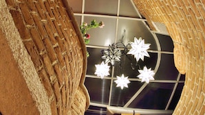 Eine Wendeltreppe mit Backsteinwänden und einem Glasboden, die zu einem Raum mit einem Kronleuchter und einem Fenster führt.