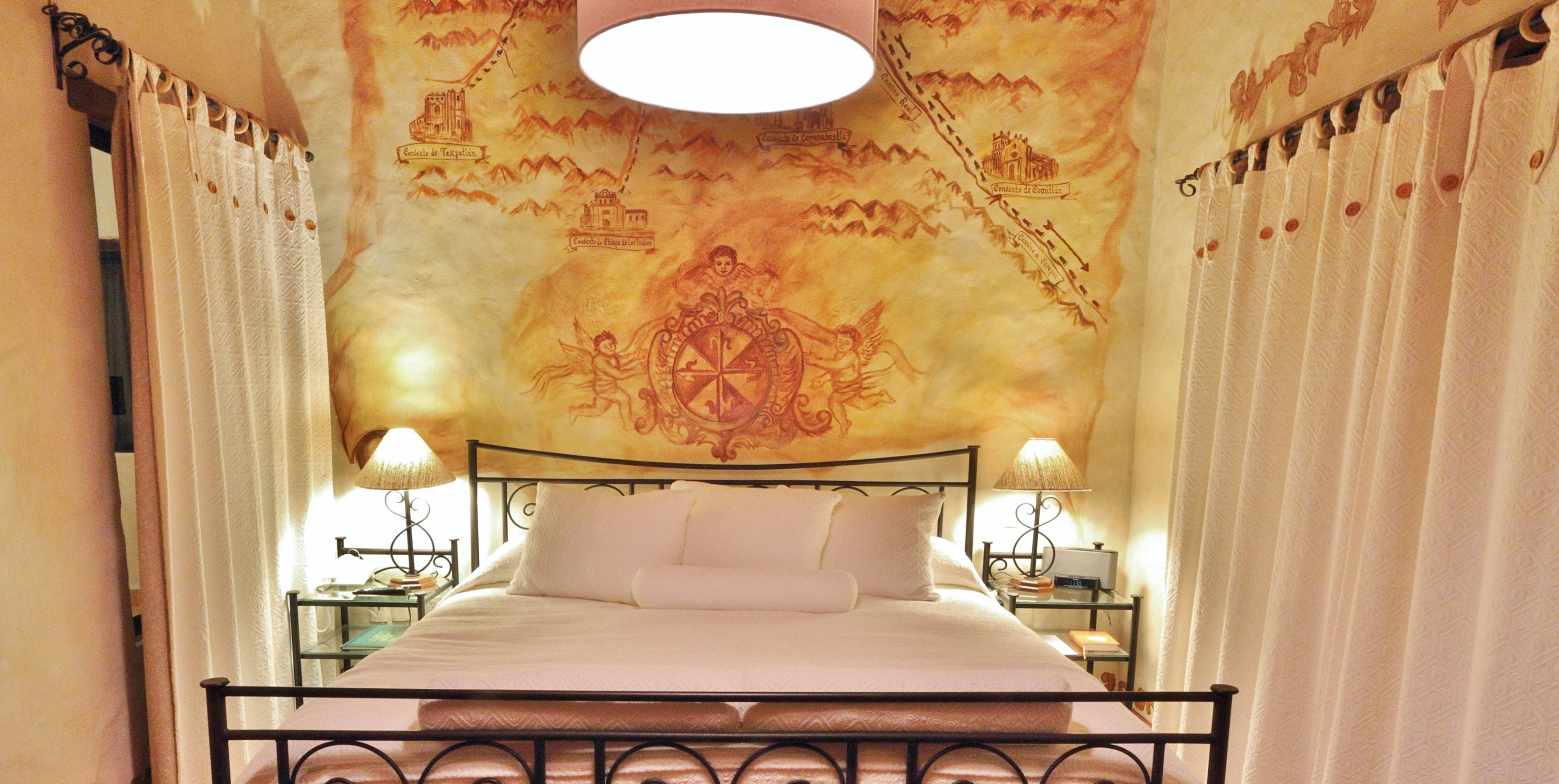 A bed with white linens, a metal frame, and two bedside tables with lamps.