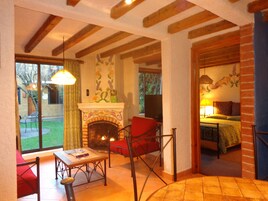 Un salon chaleureux avec une cheminée, un canapé rouge, une table basse en bois et une vue sur l’extérieur.