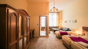 Una camera d'albergo con un ampio armadio in legno, un divano, un letto con una coperta viola e un lampadario.