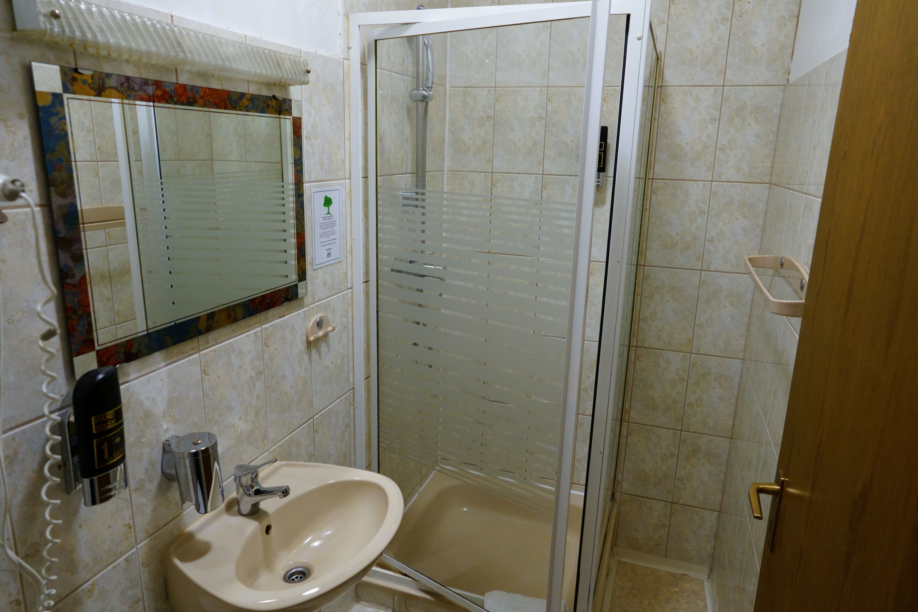 A bathroom with a sink, mirror, and shower.