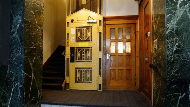 Una scala che conduce a una porta in legno con un cancello di metallo.