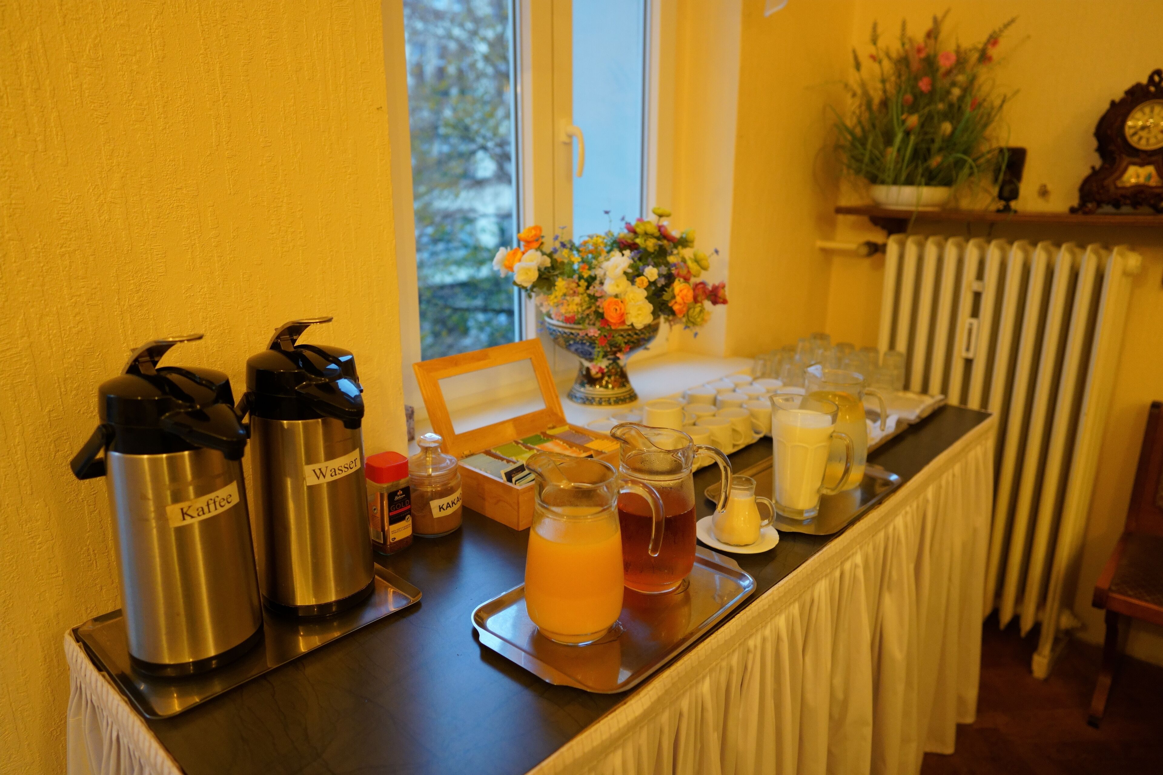 Een ontbijtbuffet met koffie- en sapsappen, een fruitschaal, en een schaal met diverse ontbijtartikelen.
