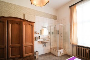 A bathroom with a wooden wardrobe, a sink, a mirror, and a shower. - Hotel Margrit (Berlin)