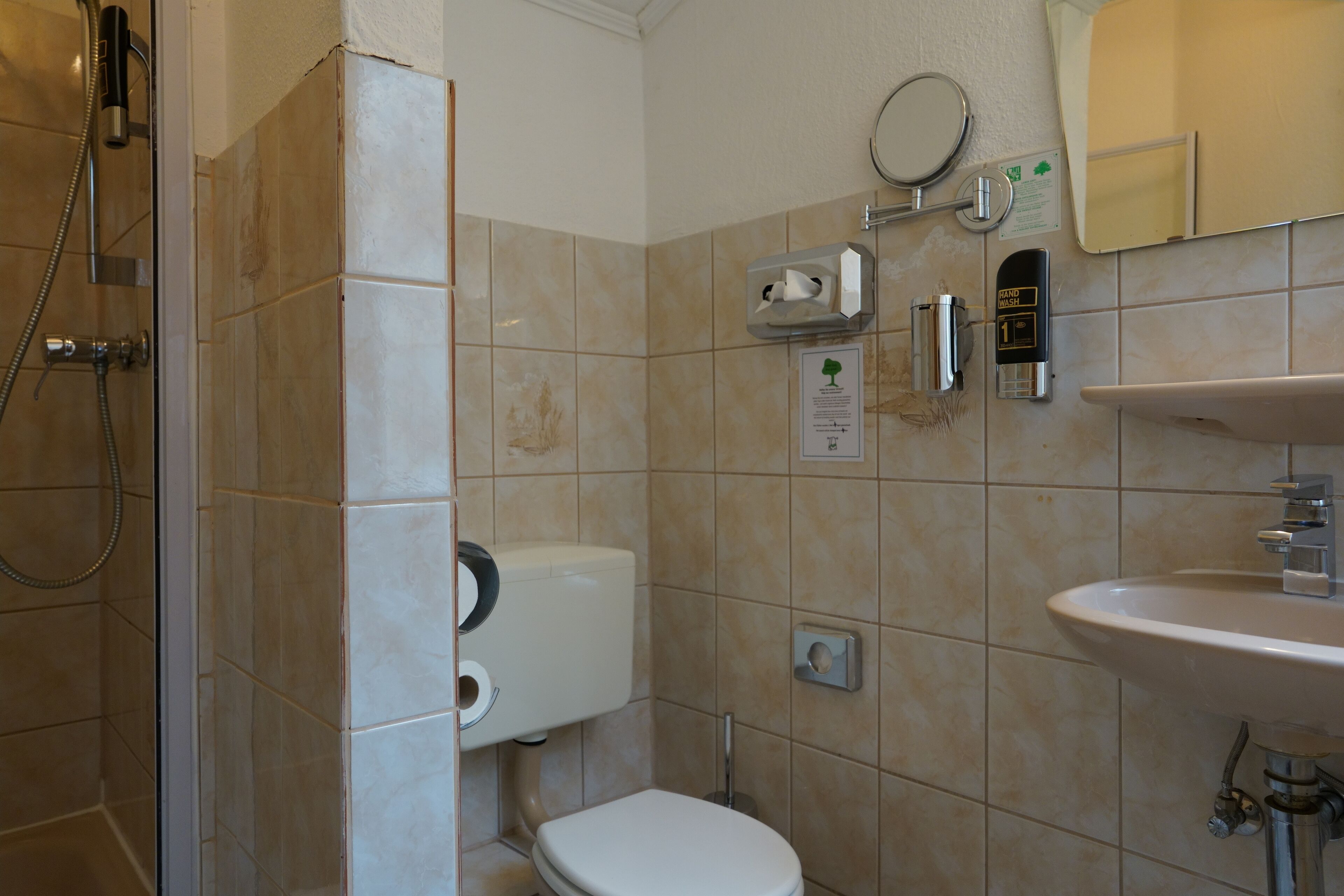 A bathroom with a toilet, sink, and shower.