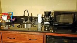 Una cocina con un lavamanos, una cafetera, un microondas y un mueble con cajones.