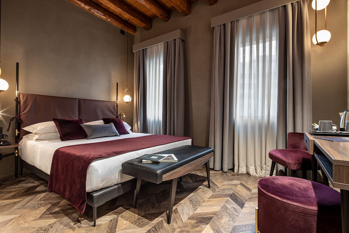 Habitación de hotel con una cama grande, un banco, un escritorio y una silla.