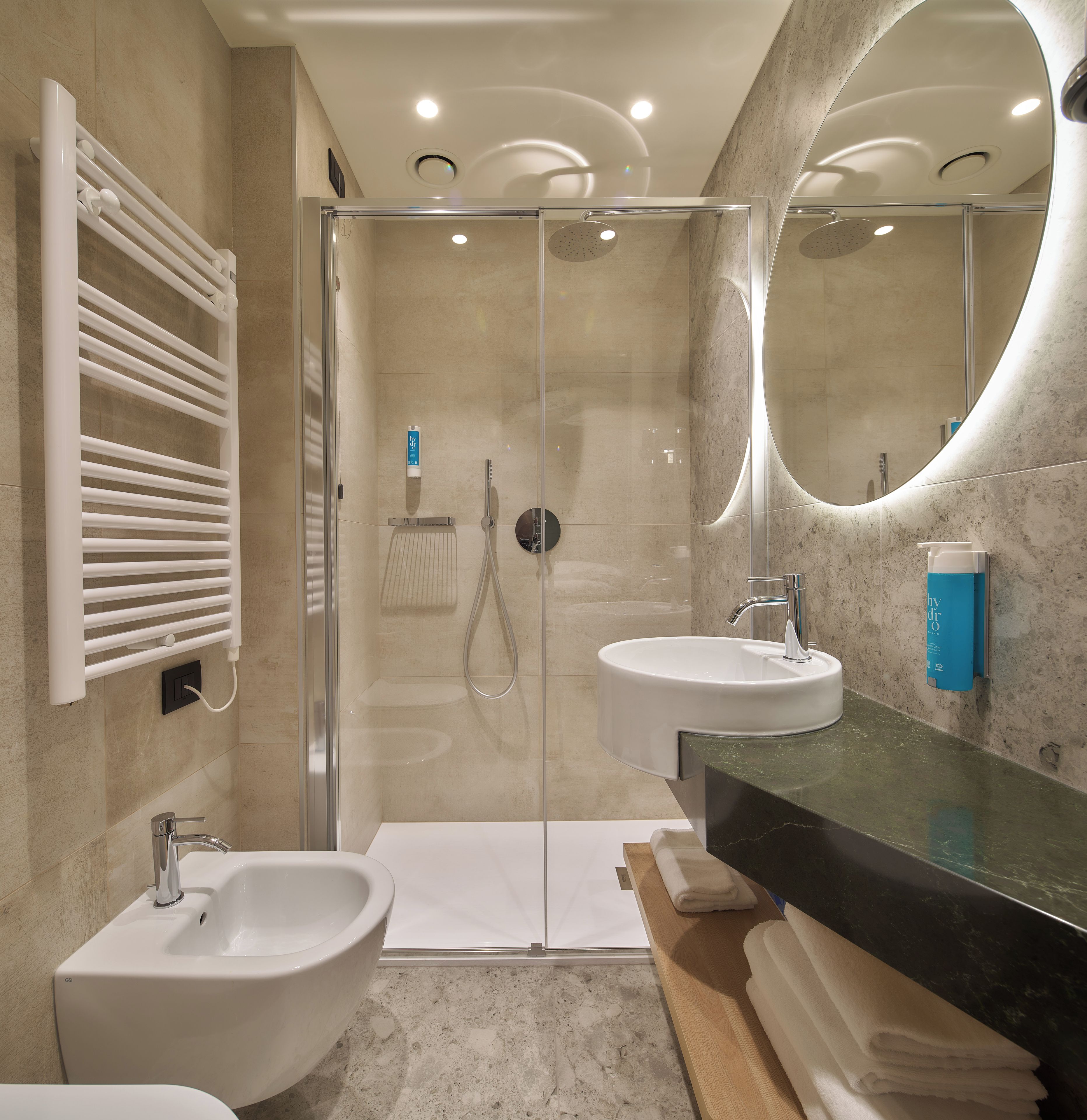 Une salle de bain moderne avec une douche à l’italienne, deux vasques et un grand miroir.