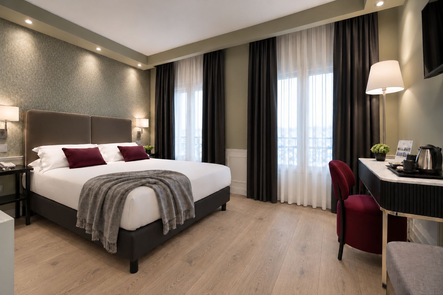 Habitación de hotel con una cama grande, un escritorio con una silla, una lámpara y vistas al exterior.