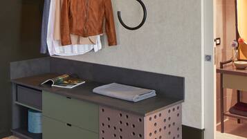 A modern bathroom with a wooden floor, a vanity with a mirror, and a towel rack with clothes.