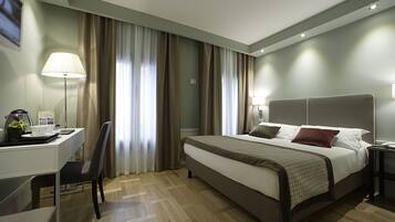 Een moderne hotelkamer met een bed, bureau, stoel en lamp.