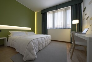 Relax in a serene space with a comfortable bed, desk, and natural light pouring in through the large window.