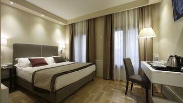 A hotel room with a bed, a desk, a chair, and a TV.