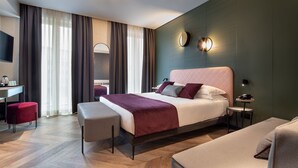Moderni hotellihuone, jossa on suuri sänky, työpöytä, tuoli ja pieni pöytä.
