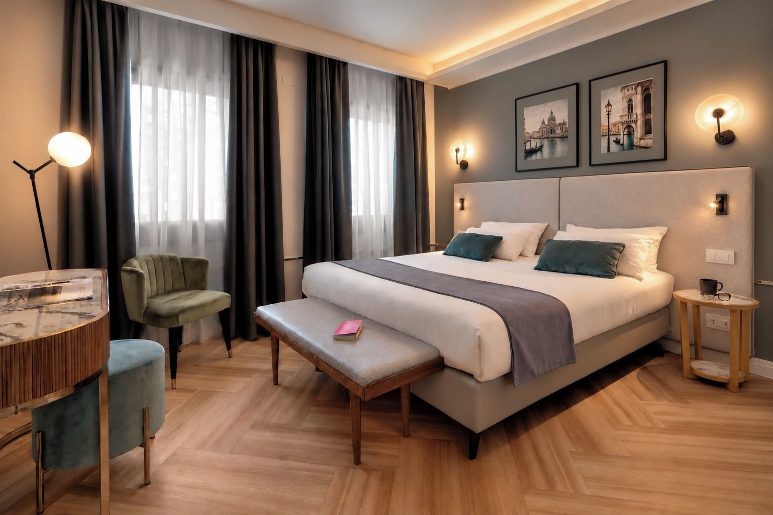 Ein modernes Hotelzimmer mit einem großen Bett, einem Schreibtisch mit Lampe, einem Sessel und einem kleinen Tisch.