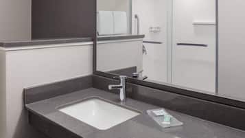 A modern bathroom with a marble sink, a mirror, and a glass shower enclosure.