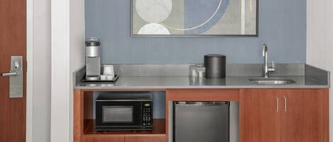 A compact kitchenette with a microwave, coffee maker, and sink.