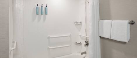 A modern bathroom with a bathtub, grab bars, a towel rack, and a shower curtain.