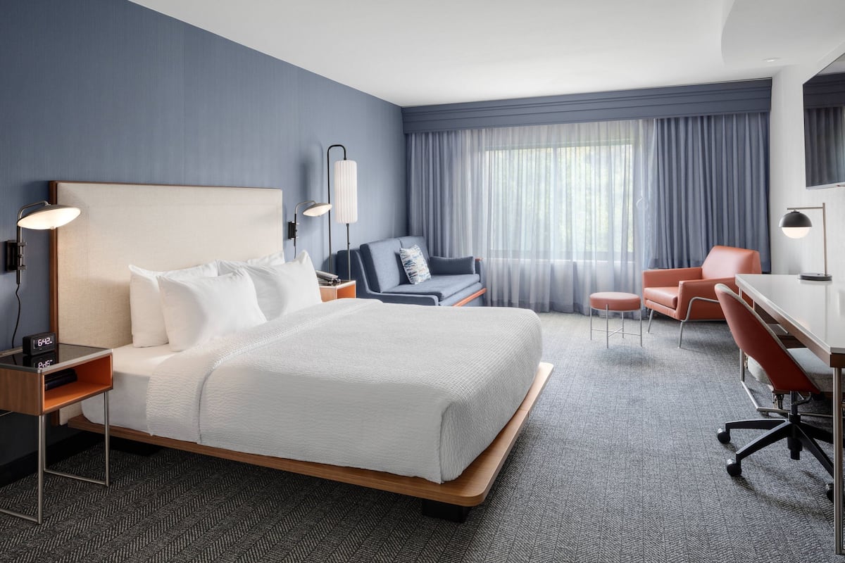Una habitación de hotel con una cama grande, un escritorio, una silla y un sofá.