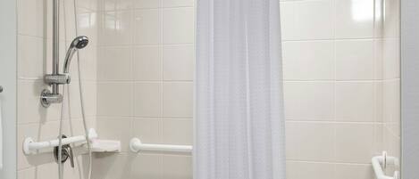 A modern bathroom with a walk-in shower, grab bars, a white bathtub, and a towel rack.