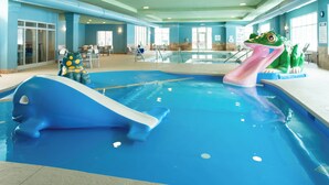 An indoor pool with a blue slide, a frog-shaped water feature, and seating areas. - Holiday Inn Express Hotel & Suites Wausau by IHG (Schofield)