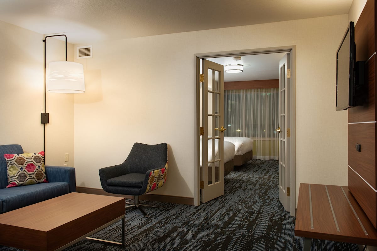 A hotel room with a sofa, armchair, and a bed.