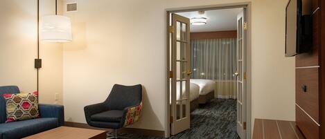 A hotel room with a sofa, armchair, and a bed.