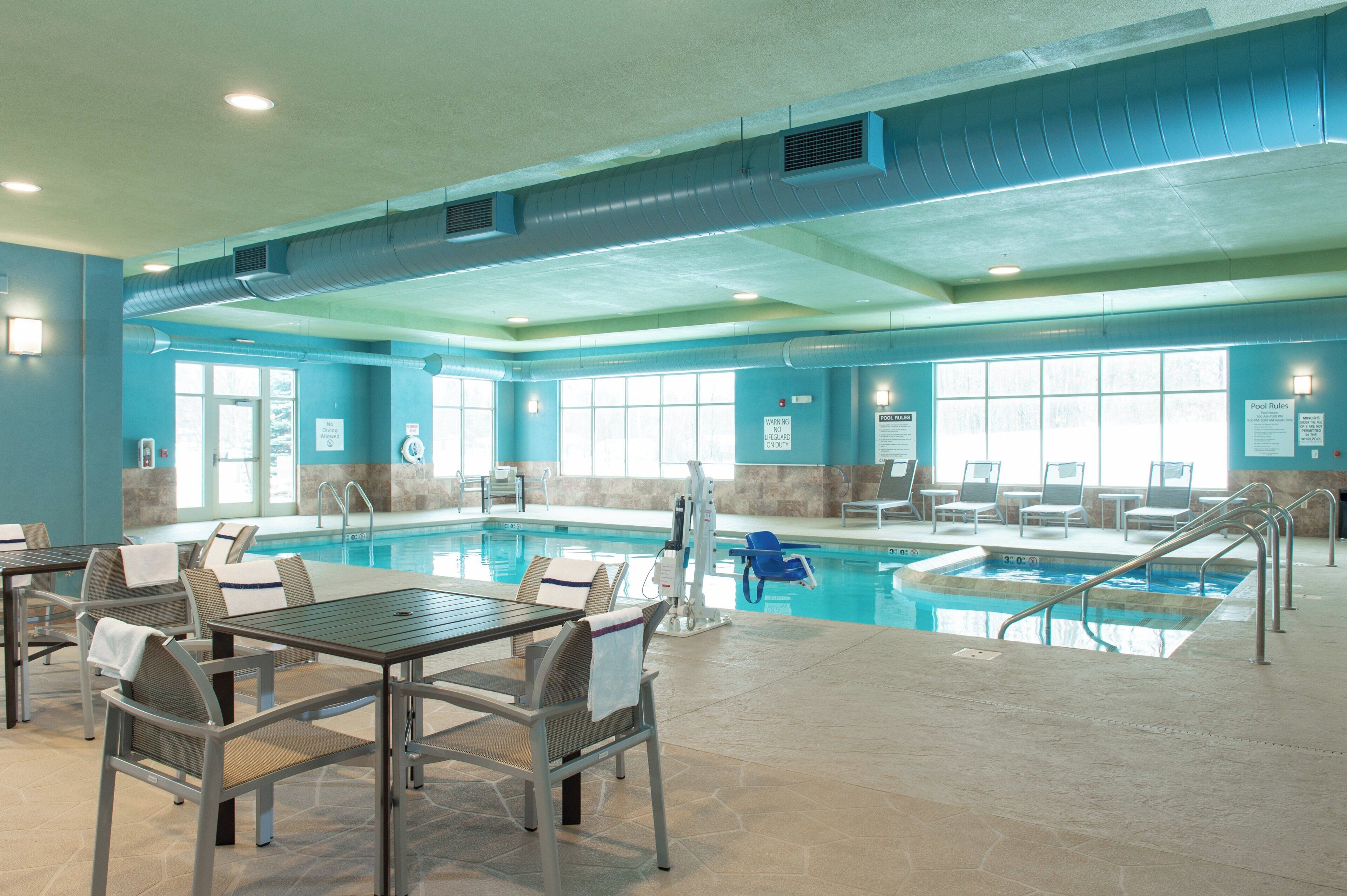 Un espace piscine comprenant plusieurs piscines, des chaises longues et une table avec des chaises.