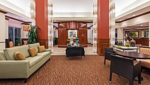 A hotel lobby with a sofa, chairs, a table, and a decorative plant. - Hilton Garden Inn Corpus Christi (Corpus Christi)