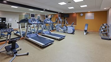 A fitness center with treadmills, elliptical machines, and a weight bench.