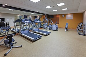 Un centre de remise en forme équipé de tapis de course, de vélos elliptiques et d’un banc de musculation.