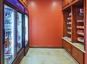 Un couloir avec un présentoir réfrigéré pour les boissons et un garde-manger rempli d’en-cas.