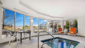 A pool area with a pool, chairs, and a table.