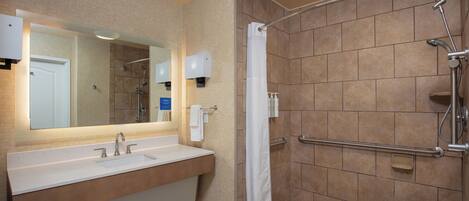 A modern bathroom with a large sink, mirror, and shower area.