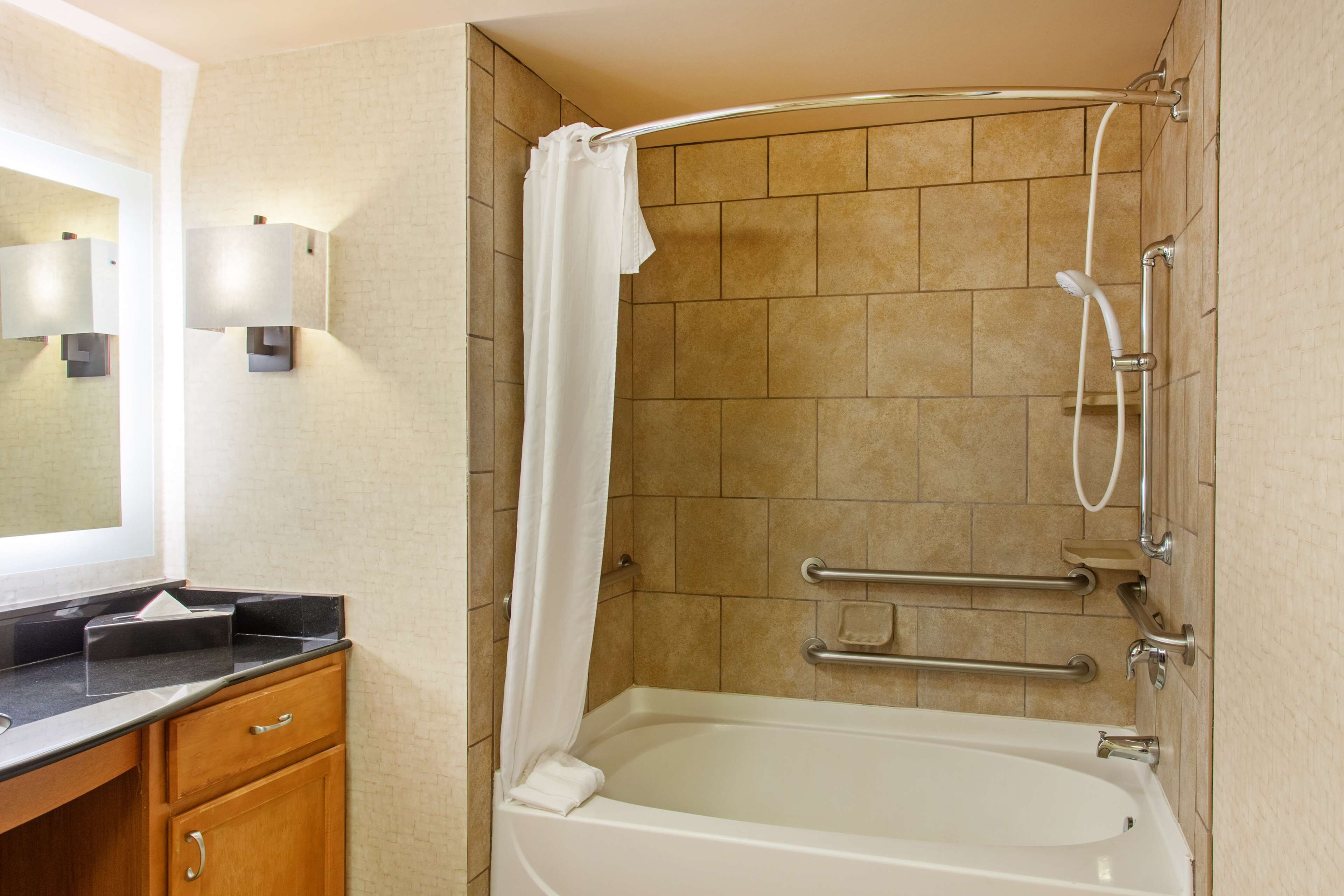 A bathroom with a bathtub, a shower, a vanity with a mirror, and a towel rack.