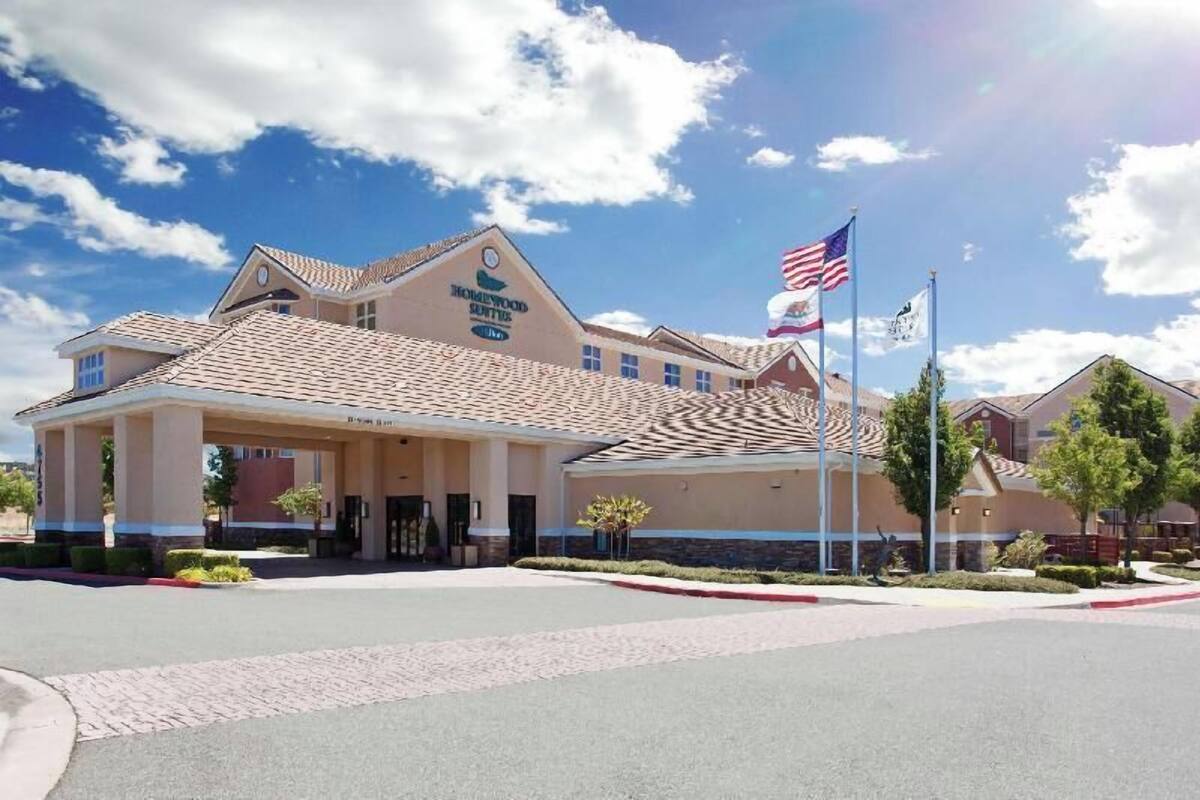 Un hotel con entrada cubierta, banderas estadounidenses y cielo despejado.