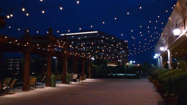An outdoor area with string lights, wooden pergolas, and seating arrangements. - Hilton Dallas/Southlake Town Square (Southlake)
