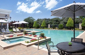 A pool area with multiple swimming pools, lounge chairs, and umbrellas. - Hilton Dallas/Southlake Town Square (Southlake)