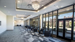A spacious hallway with a checkered carpet, modern lighting fixtures, and large windows offering a view of the outdoors. - Hilton Dallas/Southlake Town Square (Southlake)