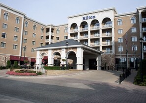 A large, multi-story hotel with a prominent "Hilton" sign, featuring a central entrance with a covered area and a landscaped garden. - Hilton Dallas/Southlake Town Square (Southlake)